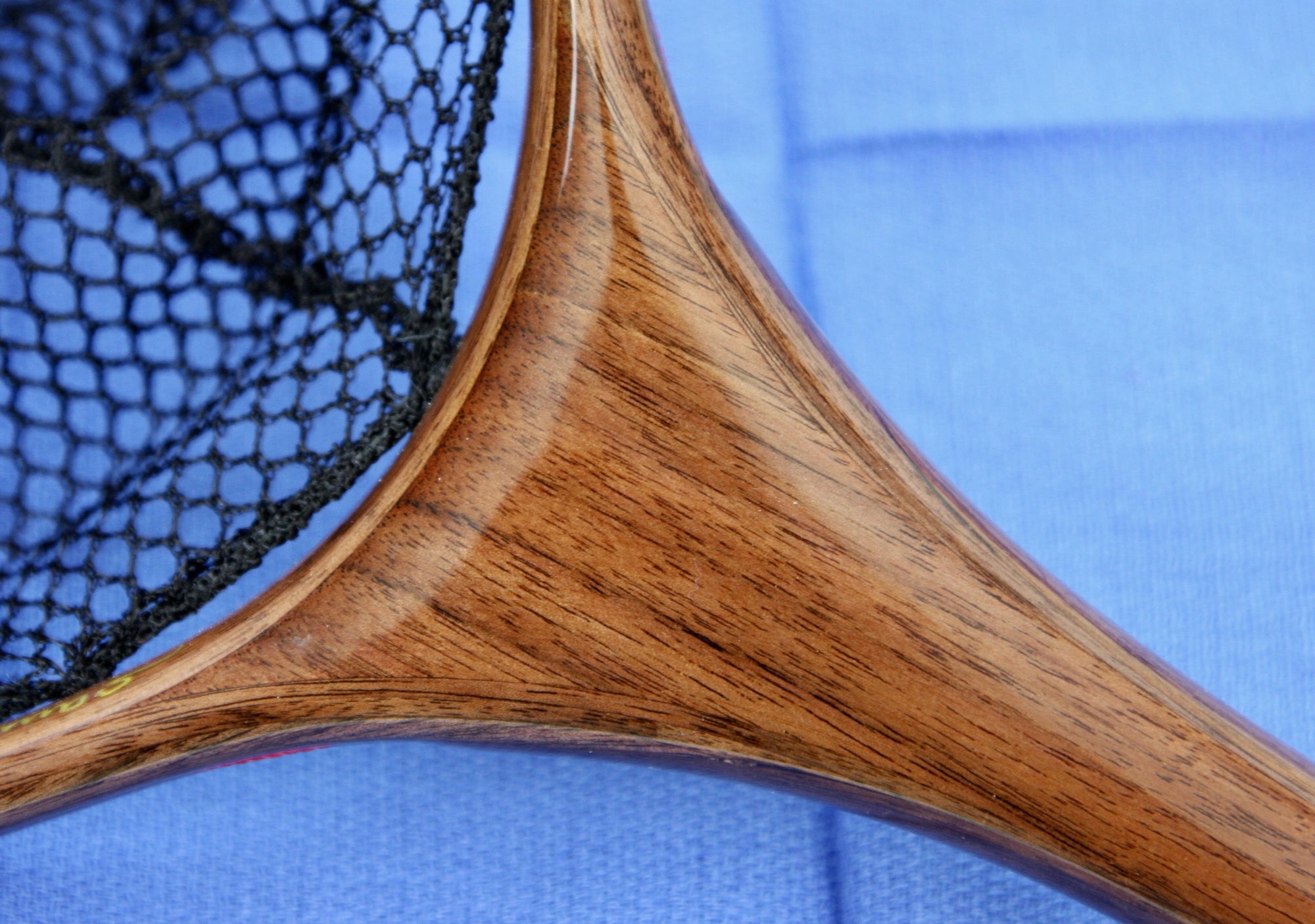 Close up of landing net handle with dark colored wood.