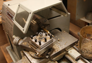 Lathe with brass rod being turned into a brass bolt.