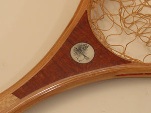 Close up of scrimshaw of dry fly inset into a fly fishing net handle. 