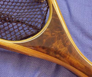 Close up of landing net handle with light and dark colored wood.